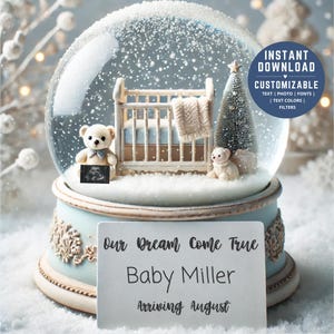 May include: A white snow globe with a baby crib, two teddy bears, and a small Christmas tree inside. The base of the snow globe is light blue with gold trim. A white card with the text "Our Dream Come True Baby Miller Arriving August" is in front of the snow globe.