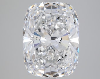 Pode incluir: Um diamante transparente de corte almofada com um ligeiro tom amarelado. O diamante tem várias pequenas inclusões pretas visíveis dentro da pedra.