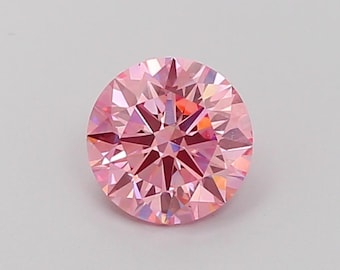 Puede incluir: Un diamante redondo rosa con talla brillante y muchas facetas. El diamante está colocado sobre un fondo blanco.
