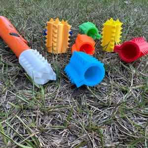 Puede incluir: Un conjunto de seis juguetes para masticar para perros de plástico texturizado y de colores. Los juguetes tienen forma de anillo y tienen diferentes colores, incluyendo naranja, amarillo, azul, verde y rojo. Los juguetes están diseñados para ayudar a limpiar los dientes y las encías de un perro.