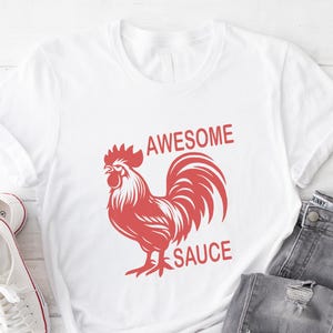 Pode incluir: Camiseta branca com um gr&aacute;fico de galo vermelho e o texto "Awesome Sauce".
