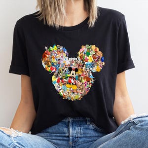 May include: Black t-shirt featuring a colorful collage of Disney characters arranged in the shape of Mickey Mouse's head. The design includes characters like Mickey, Minnie, Donald Duck, and many more. The shirt is made of a soft material.