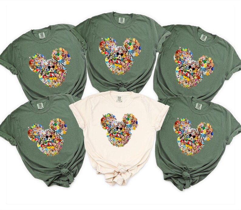 May include: A collection of six t-shirts in various colors, including olive green and cream. Each shirt features a Mickey Mouse head design composed of numerous cartoon characters. The shirts are made of a soft material.