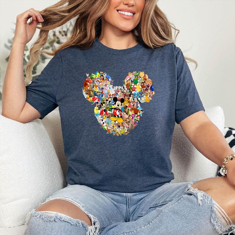 May include: A navy blue t-shirt featuring a colorful collage of Disney characters arranged in the shape of Mickey Mouse's head. The design includes characters like Mickey, Minnie, Donald, and Goofy. The shirt is made of a soft material.