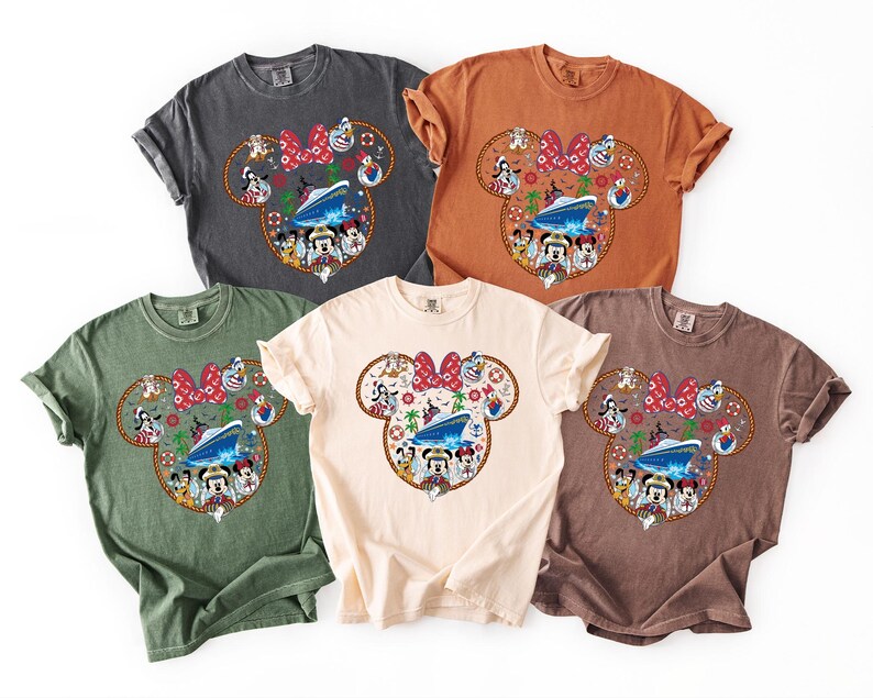 May include: Five short-sleeved t-shirts in shades of grey, orange, green, cream, and brown. Each shirt has a Mickey Mouse head design with a cruise ship, characters, and a red bow. The shirts are in various colours.