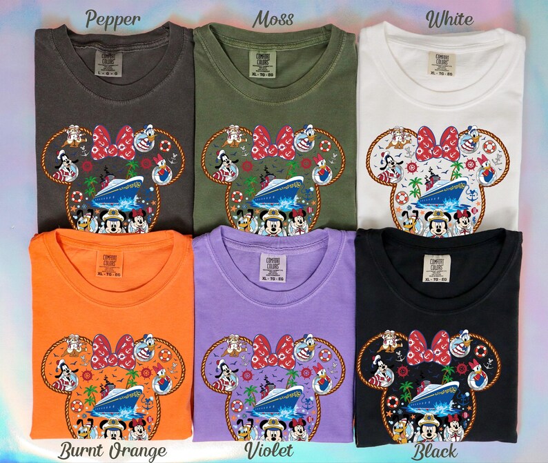 May include: Six t-shirts in colours including pepper, moss, white, burnt orange, violet, and black. Each shirt displays a Minnie Mouse head design with a cruise ship and Disney characters. The shirts are labelled with their respective colours.
