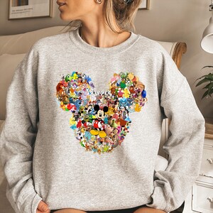 May include: A white ceramic mug with a black handle and the text "But First, Coffee" in a bold, black font. The mug is set against a blurred background, suggesting a cozy setting.