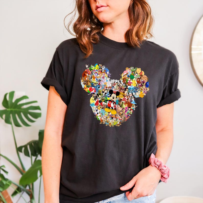 May include: Black t-shirt featuring a colorful Mickey Mouse head design composed of various Disney characters. The graphic is centrally placed on the shirt. The shirt has short sleeves and a relaxed fit, suitable for casual wear.