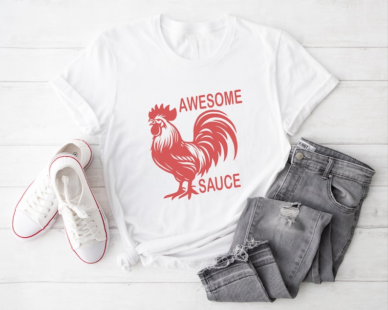 Pode incluir: Camiseta branca com um gr&aacute;fico de galo vermelho e o texto "Awesome Sauce".