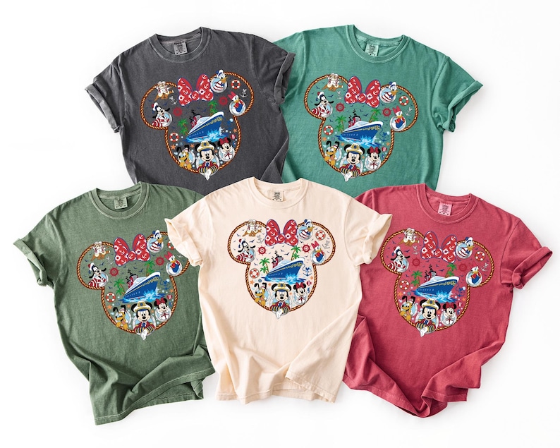 May include: Five colorful t-shirts featuring a Minnie Mouse design. The design includes a cruise ship, various cartoon characters, and a red bow. The shirts are in shades of gray, green, cream, and red.