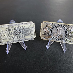 May include: Two gold-colored metal ticket replicas. The first ticket reads "One Ticket to Valhalla" with a tree, a bird, and a symbol. The second ticket reads "Act, Or Accept" with a hammer and two axes.