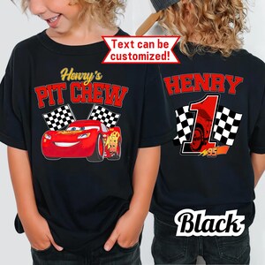 May include: Black t-shirt with a red cartoon race car and the text "Henry's PIT CREW" and checkered flags. The back of the shirt has the name "HENRY" in red, a number "1", and checkered flags. The text "Text can be customized!" is also visible.