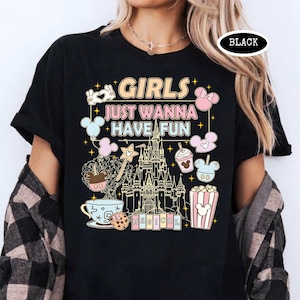 May include: Black t-shirt with the text "GIRLS JUST WANNA HAVE FUN" and various Disney-themed graphics. The design includes a castle, Mickey Mouse balloons, and other whimsical elements. The word "MAGICAL" is also present.