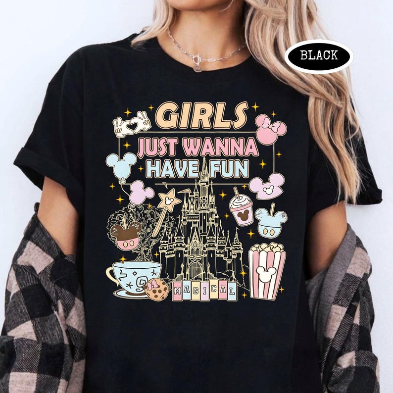 May include: Black t-shirt with the text "GIRLS JUST WANNA HAVE FUN" and various Disney-themed graphics. The design includes a castle, Mickey Mouse balloons, and other whimsical elements. The word "MAGICAL" is also present.