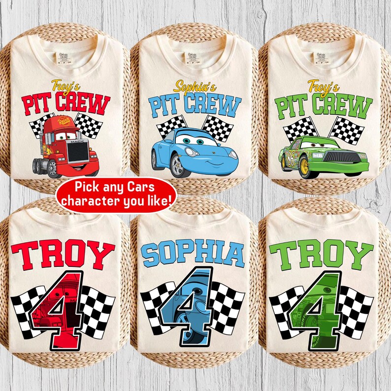 May include: Six cream-colored t-shirts with racing-themed designs. The shirts feature the text "Troy's PIT CREW", "Sophia's PIT CREW", and "Troy's PIT CREW" with car graphics. Other shirts have the names "TROY" and "SOPHIA" with the number "4" and checkered flags.