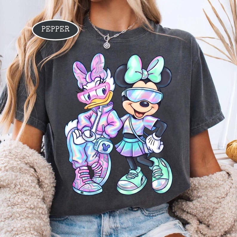May include: Dark gray t-shirt featuring Daisy Duck and Minnie Mouse in futuristic outfits. Daisy Duck wears a pink and blue jacket, sunglasses, and sneakers. Minnie Mouse wears a skirt, bow, and sneakers. The word "PEPPER" is in a white oval.