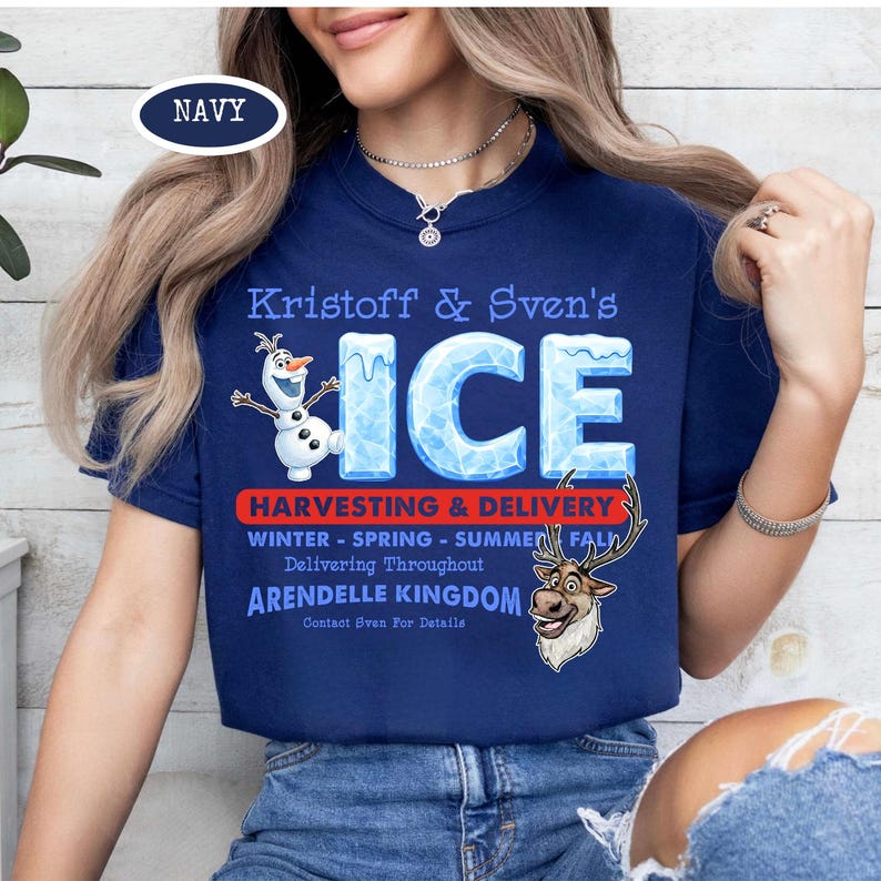 Op de afbeelding: Marineblauw T-shirt met de tekst "Kristoff & Sven's ICE" en illustraties van Olaf en Sven. Het shirt bevat ook tekst over oogsten en levering uit het koninkrijk Arendelle.