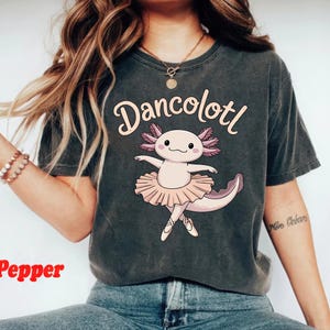 May include: A dark gray t-shirt with a graphic of a pink axolotl wearing a pink tutu and the text "Dancolottl".