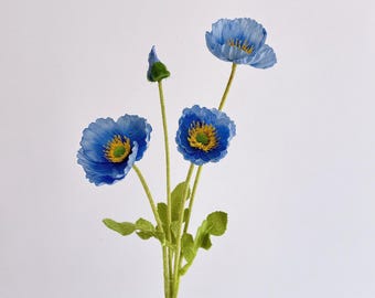 May include: A stem of blue poppy flowers with yellow centers and green leaves. The petals are a vibrant blue, and the flower centers have a yellow and green pattern. The stem is green, and the leaves are a darker green.