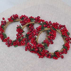 May include: Three red berry wreaths with green leaves, perfect for adding a festive touch to your home decor.