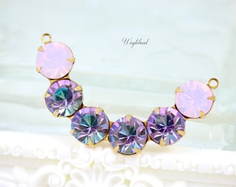 Puede incluir: Un conector de metal dorado con una fila de piedras redondas de vidrio iridiscente de color púrpura y rosa. El conector tiene forma de media luna.