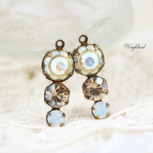 May include: Two gold-toned earring charms with a cascading design of clear iridescent crystals. The charms feature a round crystal at the top, followed by a smaller round crystal, and a larger round crystal at the bottom.