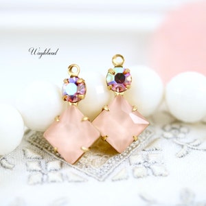 Puede incluir: Dos abalorios de pendientes de tono dorado con piedras cuadradas de cristal rosa y piedras redondas rosas iridiscentes.