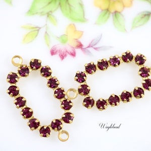 May include: Two gold-toned metal connector pieces with a loop on each end. Each piece is adorned with a circle of purple rhinestones.