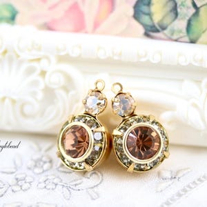 May include: Two gold-toned earrings with a round, peach-colored center stone and a smaller, clear stone above. The earrings are surrounded by smaller, clear crystals. The brand name "Waytobead" is visible.
