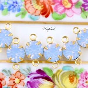 Puede incluir: Cinco conectores de charms de tono dorado con piedras de color azul claro que parecen &oacute;palo. Cada charm tiene dos anillos de salto.