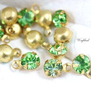 May include: Assortment of gold-toned metal embellishments with green glass rhinestones. Each embellishment has a loop for attaching to a project.