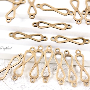 May include: A group of 16 gold-toned metal connector charms in the shape of an infinity symbol with a teardrop design. The charms have two small loops at the top for attaching to jewellery or other crafts.