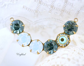 Puede incluir: Un conector de metal dorado con una fila de cuentas de vidrio azules y blancas. Las cuentas son redondas y tienen un diseño facetado. El conector está diseñado para ser utilizado en la fabricación de joyas.