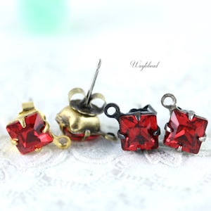 May include: Three pairs of red square crystal earrings with different earring backs. The earrings have a gold, silver, and black finish.