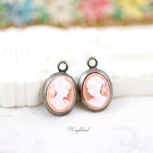 May include: Two silver oval charms with a cameo of a woman's profile in pink.