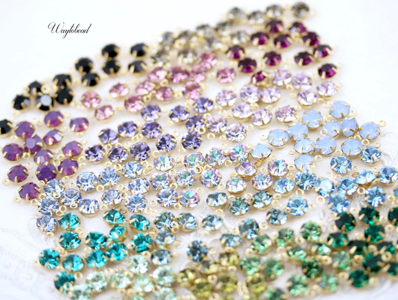 Puede incluir: Surtido de cuentas de cristal de colores con anillos de salto dorados. Las cuentas est&aacute;n dispuestas en filas, cada fila con un color diferente. Los colores incluyen negro, morado, rosa, azul claro, azul, verde y turquesa.