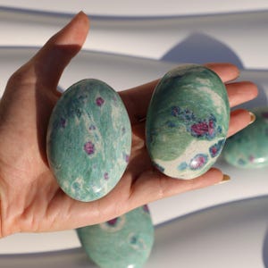 Peut inclure: Deux pierres ovales de couleur verte et blanche avec des inclusions de rubis rouges. Les pierres sont lisses et polies.