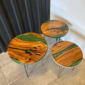 May include: Three round wooden tables with green epoxy resin inlays. The tables have black metal hairpin legs.