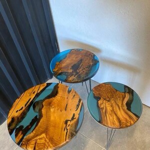 May include: Three round wooden tables with blue resin inlays. The tables have black metal hairpin legs.
