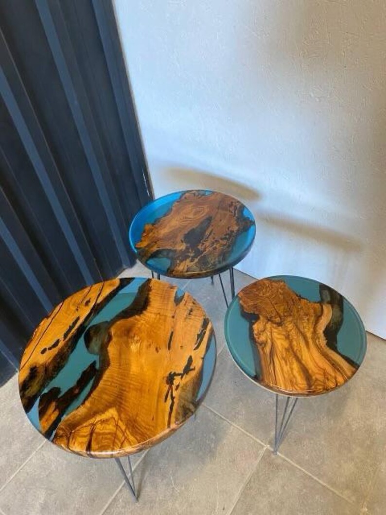 May include: Three round wooden tables with blue resin inlays. The tables have black metal hairpin legs.