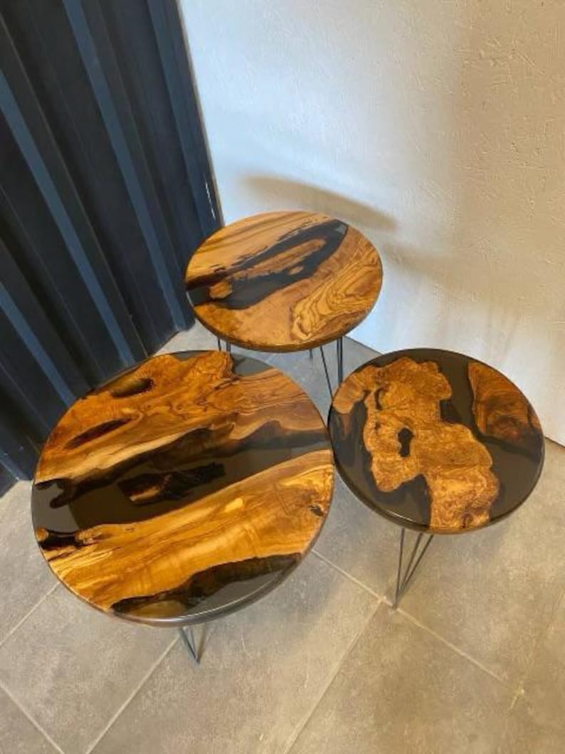 May include: Three round wooden tables with black epoxy resin inlays. The tables are different sizes and are on black metal hairpin legs.