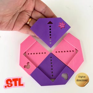 Op de afbeelding: Een veelkleurig, geometrisch 3D-geprint object in roze en paars, met een diamantachtige vorm. Het object heeft een reeks kleine gaten en uitgesneden vormen, waaronder een bloem, een hart en een Mickey Mouse-silhouet. De tekst ".STL" is zichtbaar.