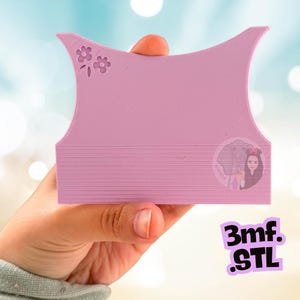 May include: A light purple, rectangular, 3D-printed plastic tool with a concave top edge and a small embossed flower design in the upper left corner. The surface features horizontal lines and a circular logo depicting an elephant and a person.