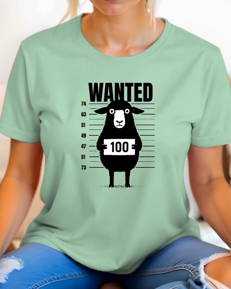 May include: A light green t-shirt featuring a black sheep illustration with the word "WANTED" above it. The sheep holds a sign with the number "100" on it, against a police lineup background.