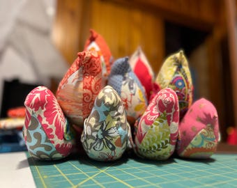 May include: A group of colorful fabric birds, each with a different pattern, are arranged in a cluster. The birds are made of patchwork fabric and have a variety of colors, including pink, blue, green, and yellow.