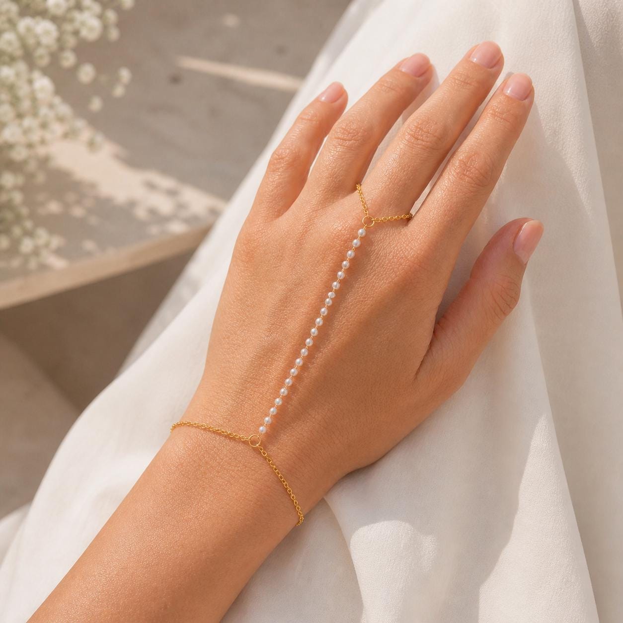 Gold-tone stainless steel pearl hand chain draped across wrist for elegant bridal hand jewelry