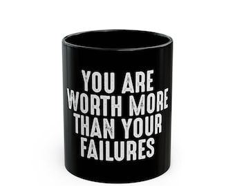 以下が含まれることがあります： 「You are worth more than your failures」という白い文字が書かれた黒いコーヒーカップ。