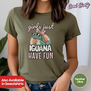 Puede incluir: Camiseta verde oliva jaspeado con un gráfico de una iguana de dibujos animados con gafas de sol y un lazo rosa. El texto dice "girls just IGUANA HAVE FUN". La camiseta también tiene el texto "Also Available in Sweatshirts".