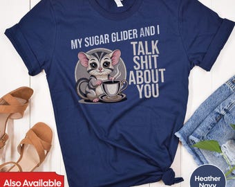 May include: A navy blue t-shirt with a cartoon sugar glider holding a cup of coffee. The text "My sugar glider and I talk shit about you" is printed on the shirt.