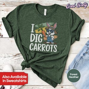 May include: A green t-shirt with a cartoon bunny wearing sunglasses and holding a carrot. The text "I DIG CARROTS" is printed on the shirt.